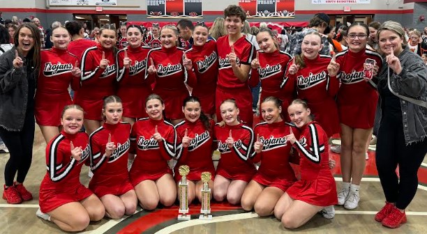 Trojans cheer team in red uniforms posing with two trophies