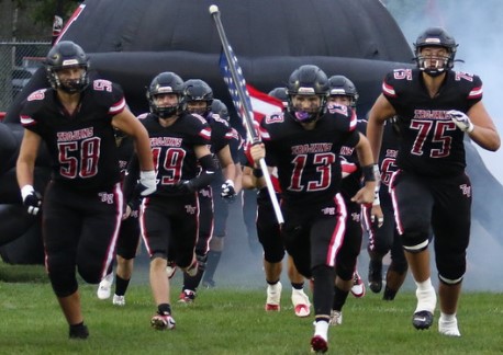 Trojans football team running onto the field in the new black uniforms