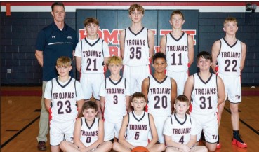 Middle school boys basketball team and coach in white Trojans uniforms