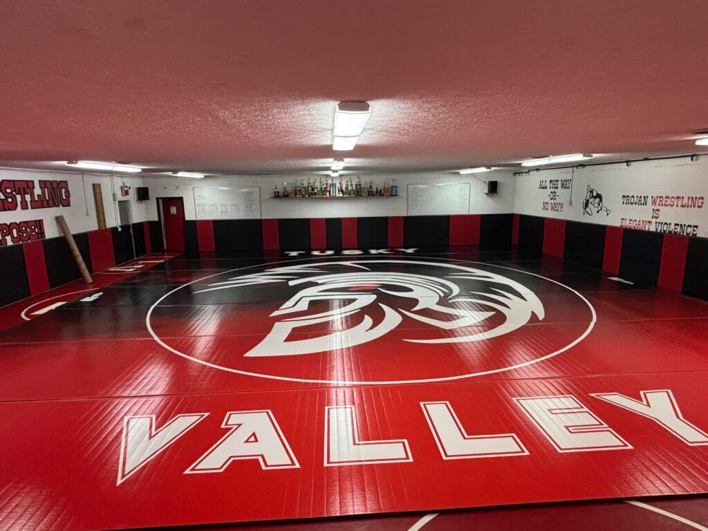 Wrestling room with the new red and black mat and the Tusky Valley Trojan helmet logo at center